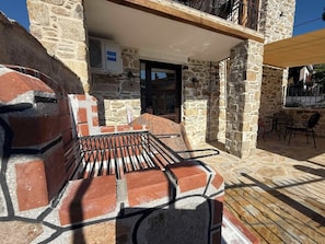 A stone building with a brick barbecue area and outdoor seating. - White Stone Apartments - Ground Floor (Sithonia)