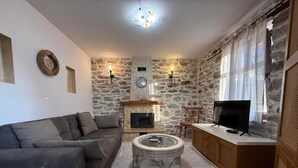 Ein Wohnzimmer mit Steinwand, Kamin, Sofa, Couchtisch, Fernseher und Schrank.
