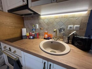 A kitchen with a wooden countertop, a sink, a stove, and various kitchen items. - White Stone Apartments - Ground Floor (Sithonia)