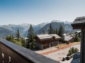 A mountain lodge with a stone facade, wooden exterior, and a view of snow-capped mountains. - Courchevel 1850: Apartment for 4 near slopes, wifi (Courchevel)