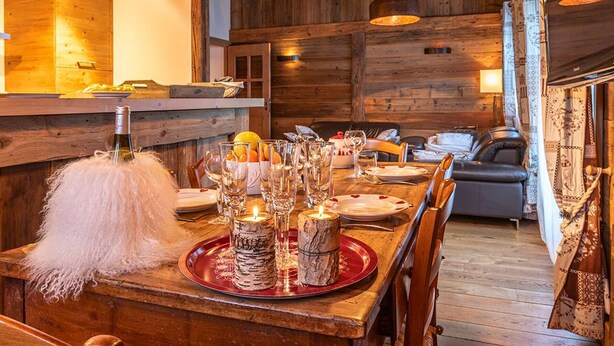 Un intérieur en bois avec une table à manger dressée pour le repas, un canapé et une lampe.