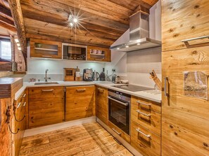 A kitchen with wooden cabinets, stainless steel appliances, and a built-in oven. - Charming 81m² Apt in Courchevel 1850 - Central, Near Slopes, Sleeps 4, Balconies, Luxury Amenities (Courchevel)