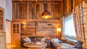 Un intérieur rustique avec un mur en bois, un canapé en cuir, une table ronde en bois et un luminaire suspendu.