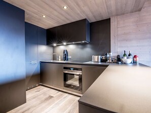 A modern kitchen with built-in appliances, a wooden ceiling, and a minimalist design. - Cozy 51m² Apt, Sleeps 4 - Central Courchevel, Near Slopes, Fireplace, Balcony, Spa Access (Courchevel 1550)