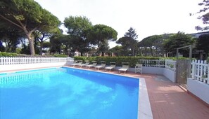 A swimming pool with lounge chairs and a white fence. - Family Flat With Furnished Outdoor Space (Lignano Sabbiadoro)