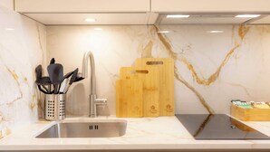 A kitchen with a marble backsplash, stainless steel sink, and wooden cutting boards. - Premium Studio 5 at The Orange Door Little Venice (Greater London)