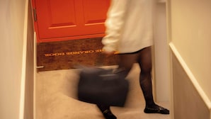 A person walking down a hallway with a red door and a carpet with 'THE OAKLAND HOTEL' text. - Premium Studio 5 at The Orange Door Little Venice (Greater London)