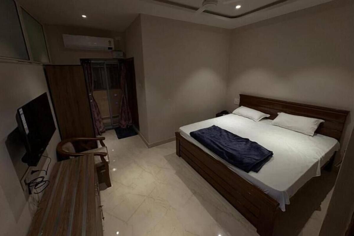 A bedroom with a bed, a desk, a chair, and a television.