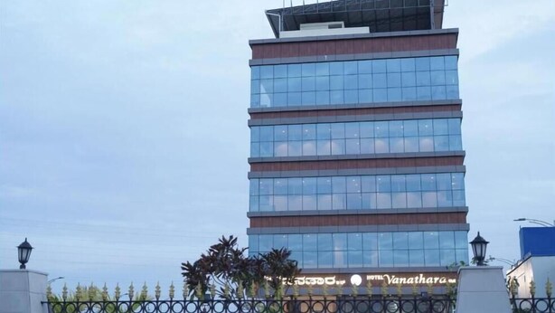 Ein mehrstöckiges Gebäude mit moderner Glasfassade und flachem Dach, mit Hinweisschild, das es als Hotel kennzeichnet.