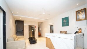 Ein Hotel-Empfangsbereich mit Marmorzauber, einer Couch, einer Treppe und einem gerahmten Bild an der Wand.