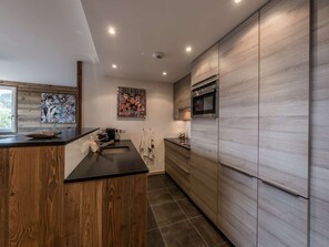 Eine moderne Küche mit Holzschränken, einer schwarzen Arbeitsplatte und einem Edelstahlbackofen.