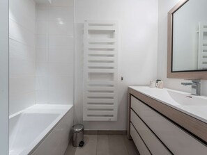 Ein modernes Badezimmer mit Badewanne, Toilette, Waschbecken und Spiegel.
