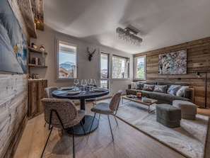 Ein modernes Wohnzimmer mit einem runden Esstisch, gemusterten Stühlen, einer Couch und einem Kamin.