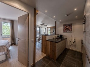 Ein modernes Hotelzimmer mit einem großen Bett, einer Holztür, einer Küchenzeile und einem Badezimmer mit Handtüchern.