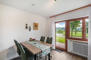 Ein Essbereich mit Tisch, Stühlen, Blick durch eine Glastür und einer Heizung.