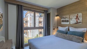 Habitación de hotel con una cama grande, un escritorio y vistas a un edificio con balcones.