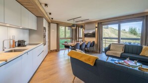 Una cocina moderna con comedor, sofá y ventanas amplias con vistas al exterior.