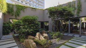 A courtyard with a stone pathway, large rocks, and greenery.
