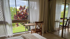 Un dormitorio con un ventanal grande, un escritorio de madera, una silla y una cama.