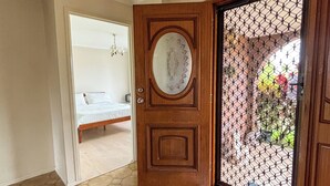 Una habitación con piso de patrón hexagonal, una puerta de madera con panel de vidrio y una lámpara colgante.