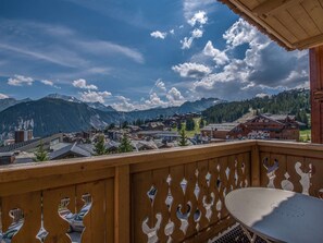 Ein Balkon mit Blick auf eine Bergstadt, Holzbalkone und ein Tisch.