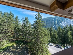 Ein Blick auf eine Berglandschaft durch ein Fenster, mit dichtem Wald und einem Parkplatz im Vordergrund.