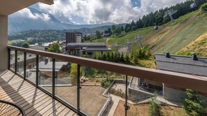 A balcony with a view of a ski resort, including a chairlift and buildings. - Modern apartment Courchevel 1550, 4 people, parking, wifi (Courchevel)