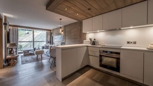 A modern kitchen with a wooden ceiling, large windows, and a dining area with a view. - Modern apartment Courchevel 1550, 4 people, parking, wifi (Courchevel)