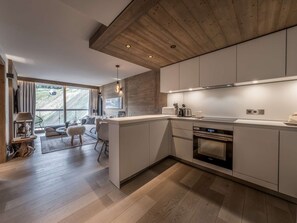 A modern kitchen with a wooden ceiling, large windows, and a dining area with a view. - Modern apartment Courchevel 1550, 4 people, parking, wifi (Courchevel)