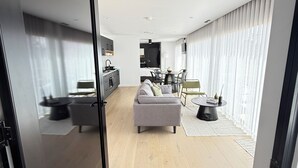 A modern living room with a sofa, dining table, and kitchen area.