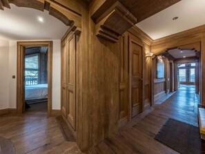 A wooden hallway with a staircase, wooden doors, and a view of an outdoor deck. - Courchevel 1850: Ski-in/ski-out apartment, 3 bedrooms, Wi-Fi, parking (Courchevel)