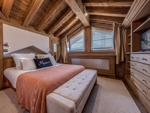 A bedroom with a wooden ceiling, a bed with a pink blanket, a bench, and a dresser. - Courchevel 1850: Ski-in/ski-out apartment, 3 bedrooms, Wi-Fi, parking (Courchevel)