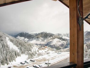 Bergzicht vanaf een houten chalet met een skipiste op de achtergrond.