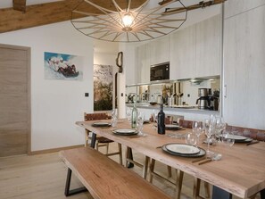 Een eethoek met een houten tafel voor zes personen, een bank en een moderne hanglamp.
