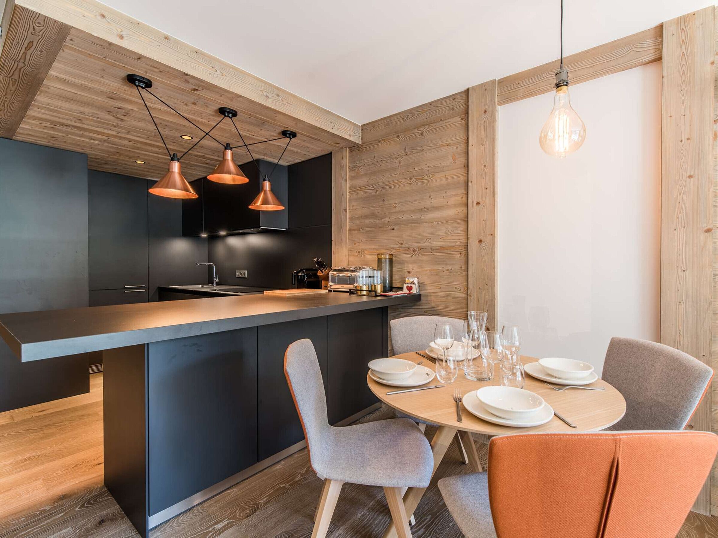 A modern kitchen with dark cabinets, a wooden island, and pendant lighting.