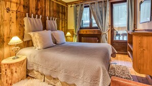 Quarto com painéis de madeira, cama, cortinas e janela.