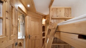 A wooden interior with bunk beds, a door leading to a bathroom, and built-in shelves. - Studio Courchevel 1850 - Sleeps 4 - Ski-in/Ski-out with covered parking (Courchevel)