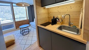 Una cucina moderna con un piano di lavoro in legno, un lavello e una finestra con vista su un paesaggio innevato.