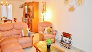 A living room with a sofa, armchair, and a coffee table with a plant. - Garden House 3bedrooms, parkingFREE, wifi, 15minLR (Nieul-sur-Mer)