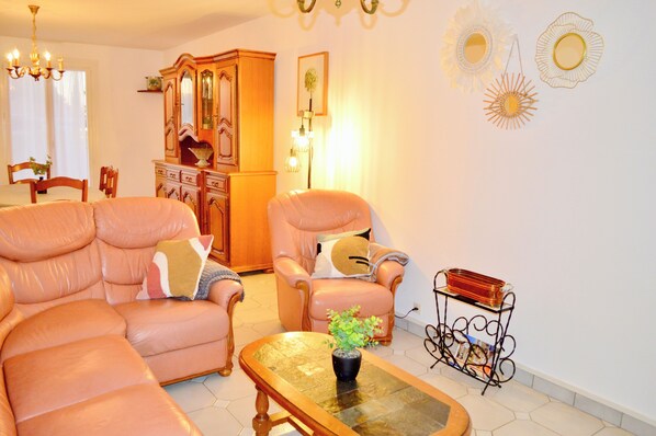 A living room with a sofa, armchair, and a coffee table with a plant.