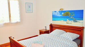 A bedroom with a wooden bed, a nightstand, a painting of a beach scene, and a window with curtains. - Garden House 3bedrooms, parkingFREE, wifi, 15minLR (Nieul-sur-Mer)