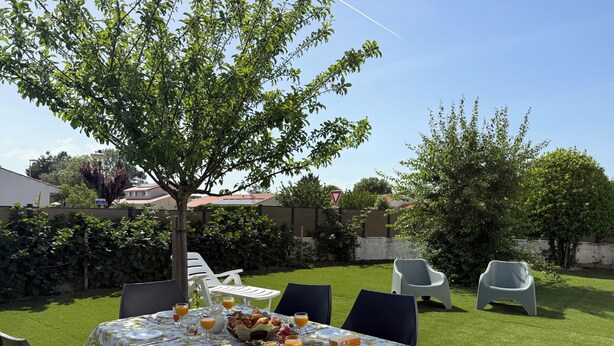 A table set outdoors with a tablecloth, chairs, and a tree in the background. - Garden House 3bedrooms, parkingFREE, wifi, 15minLR (Nieul-sur-Mer)