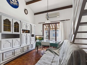 A room with a dining table, chairs, a sofa, a large cabinet, and a window with curtains. - Terraced house - 4 guests (Le Grau d'Agde)