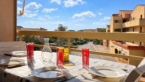 En balkon med et spisebord, med udsigt over et boligområde.