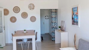Un salon moderne comprenant un coin repas, un canapé, un téléviseur et des œuvres d’art décoratives au mur.