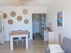 Ein modernes Wohnzimmer mit Essbereich, einer Couch, einem Fernseher und Wandkunst.