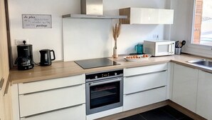 Une cuisine moderne équipée d’un four encastré, d’une machine à café, d’un four à micro-ondes et d’un panneau affiché sur le mur.