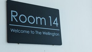 Un letrero con la inscripción 'Habitación 14' y 'Bienvenidos al Wellington'.