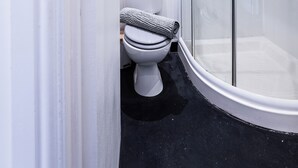 Un baño moderno con ducha de vidrio, inodoro y lavamanos.