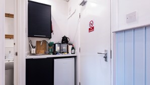 Una kitchenette compacta con refrigerador, lavamanos y microondas.